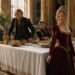 Woman in a burgundy gown walking away from two men beside a banquet table