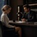 Lucia sits across from Lucas at his desk during a tense private conversation in his office.