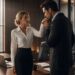 Lucas kisses Lucia's hand as they stand together beside his desk in a modern office.