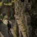 Aiden looking up at Tess as she sits reading beneath a tree above the castle ruins