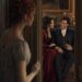 Tess watching from a doorway as Aiden laughs with an elegant dark-haired woman in red