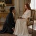 Aiden kneeling before Tess as she sits with a book in an ornate bedroom chair